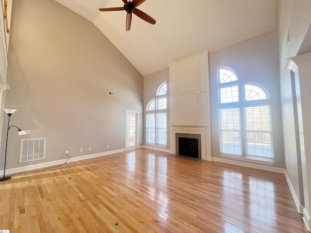 unfurnished living room with ceiling fan, a healthy amount of sunlight, light wood-type flooring, and high vaulted ceiling