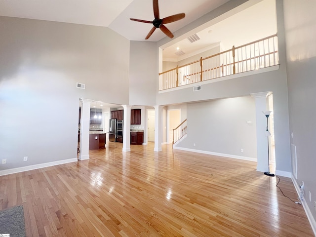 unfurnished living room featuring a high ceiling, light hardwood / wood-style flooring, and ceiling fan