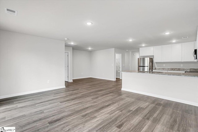 kitchen with white cabinetry, appliances with stainless steel finishes, light wood-type flooring, and light stone counters