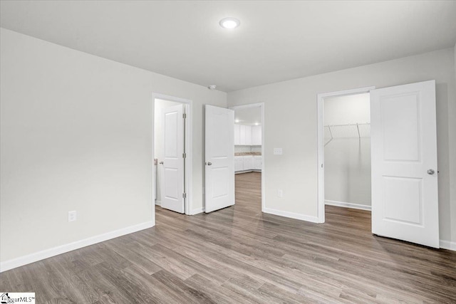 unfurnished bedroom with a walk in closet, light hardwood / wood-style floors, and a closet