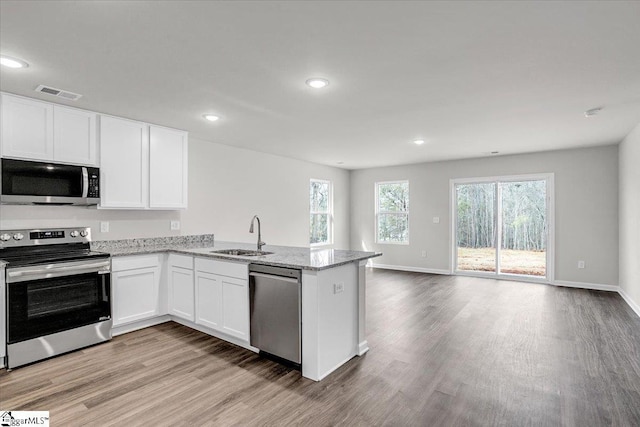 kitchen featuring sink, white cabinetry, light hardwood / wood-style flooring, appliances with stainless steel finishes, and kitchen peninsula