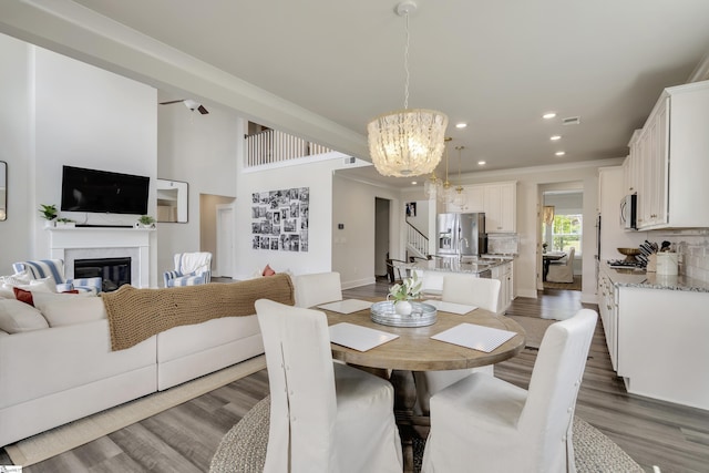 dining area with crown molding, hardwood / wood-style floors, and ceiling fan with notable chandelier