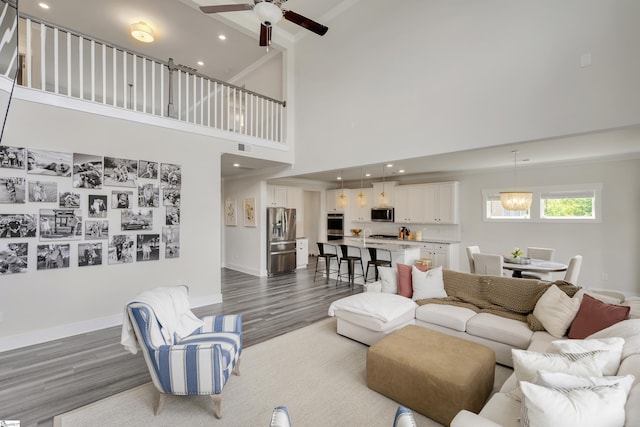 living room featuring ceiling fan, dark hardwood / wood-style flooring, and a towering ceiling