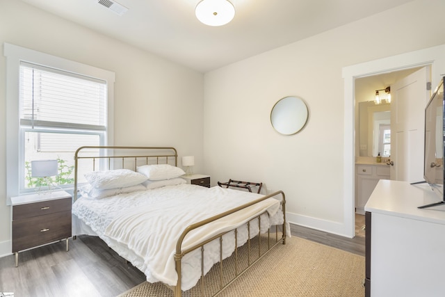 bedroom with hardwood / wood-style flooring and ensuite bath