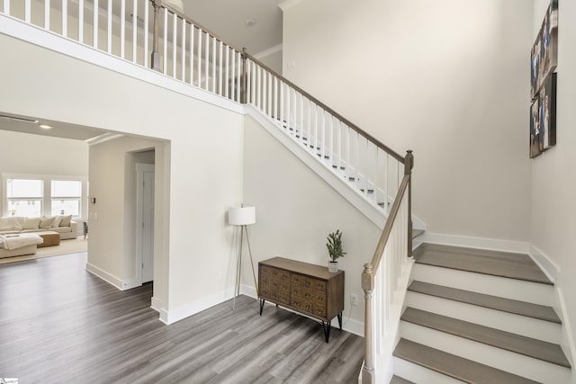 stairway with hardwood / wood-style floors and a high ceiling