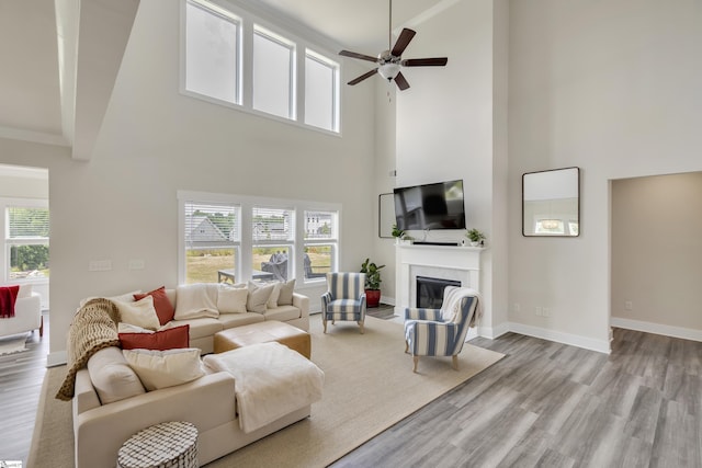 living room featuring a towering ceiling, light hardwood / wood-style floors, and ceiling fan