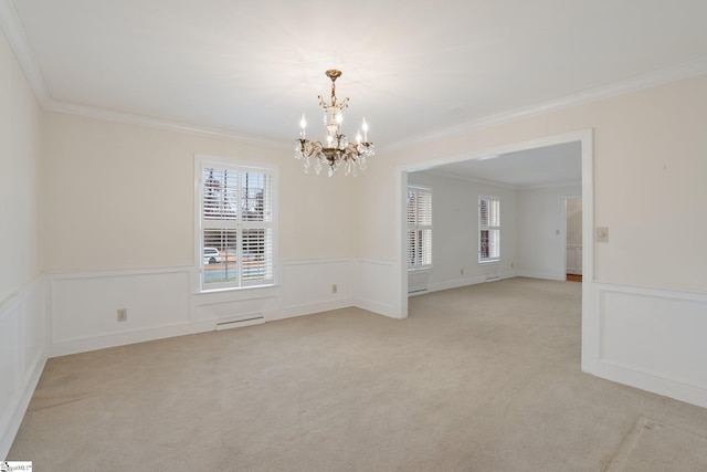 carpeted spare room featuring ornamental molding and a chandelier