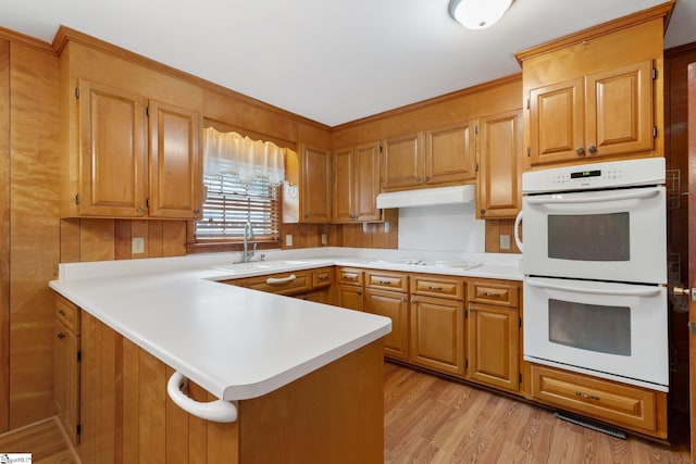 kitchen featuring kitchen peninsula, sink, light hardwood / wood-style floors, and white appliances