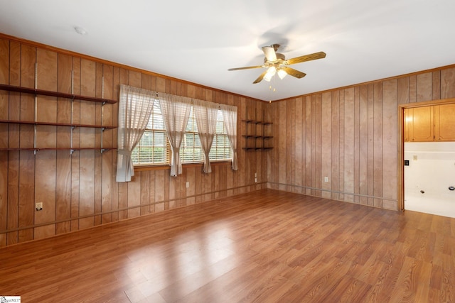 empty room featuring hardwood / wood-style floors, ceiling fan, and wooden walls