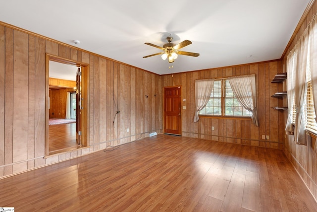 spare room featuring ceiling fan, wood walls, and wood-type flooring