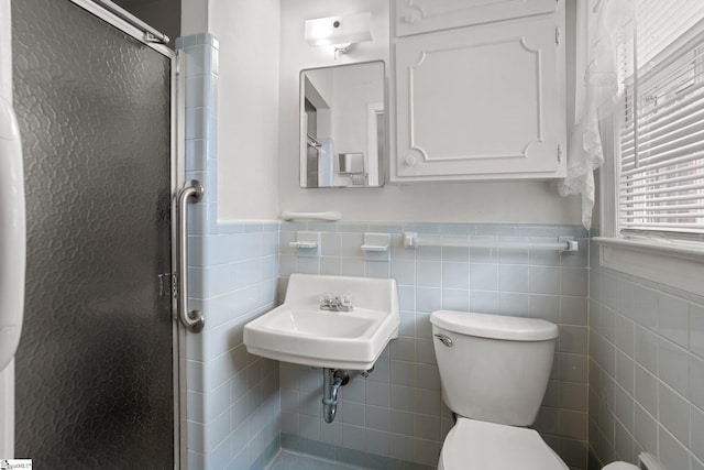 bathroom with sink, toilet, an enclosed shower, and tile walls