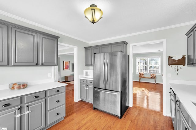 kitchen with gray cabinetry, ornamental molding, stainless steel appliances, and light hardwood / wood-style flooring