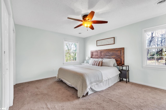 bedroom with a textured ceiling, light colored carpet, and ceiling fan