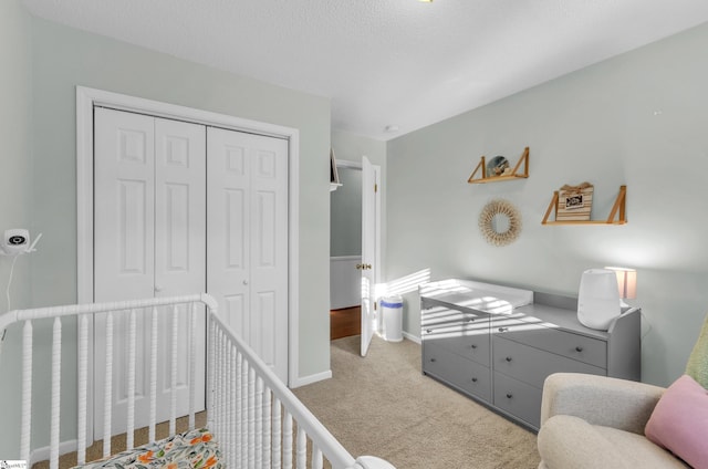 carpeted bedroom with a closet, a nursery area, and a textured ceiling