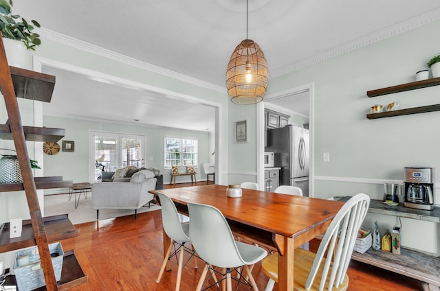 dining space featuring crown molding and light hardwood / wood-style flooring