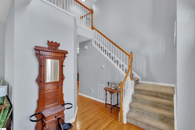 stairway with wood-type flooring and a high ceiling