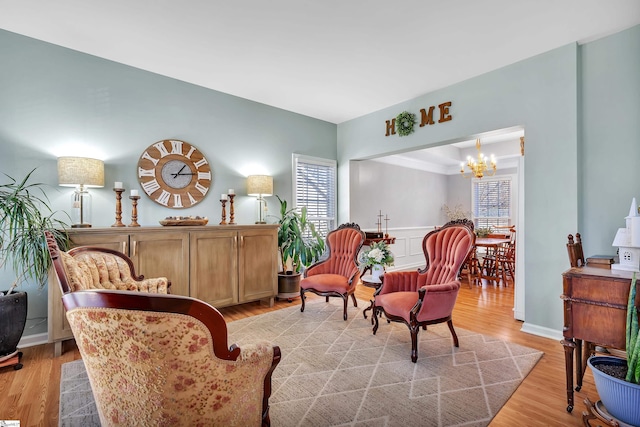 sitting room with light wood-type flooring, a wealth of natural light, and an inviting chandelier