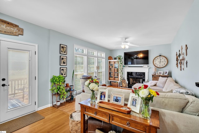 living room with a high end fireplace, wood-type flooring, and ceiling fan