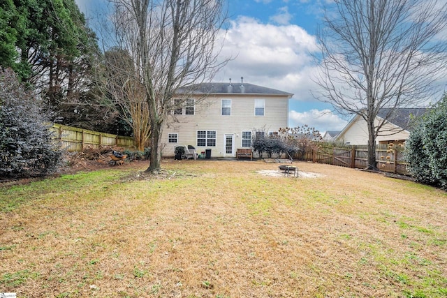 rear view of house with a yard and a fire pit