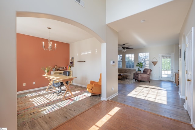 interior space featuring ceiling fan with notable chandelier and hardwood / wood-style flooring