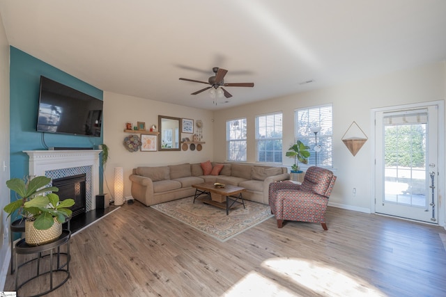 living room with hardwood / wood-style floors, ceiling fan, and a tiled fireplace