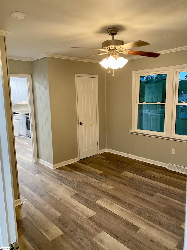 empty room with dark hardwood / wood-style flooring, ceiling fan, and ornamental molding