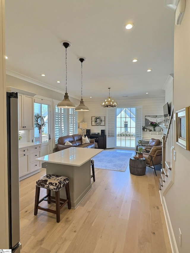 kitchen featuring stainless steel fridge, white cabinetry, light hardwood / wood-style flooring, a kitchen island, and a breakfast bar area