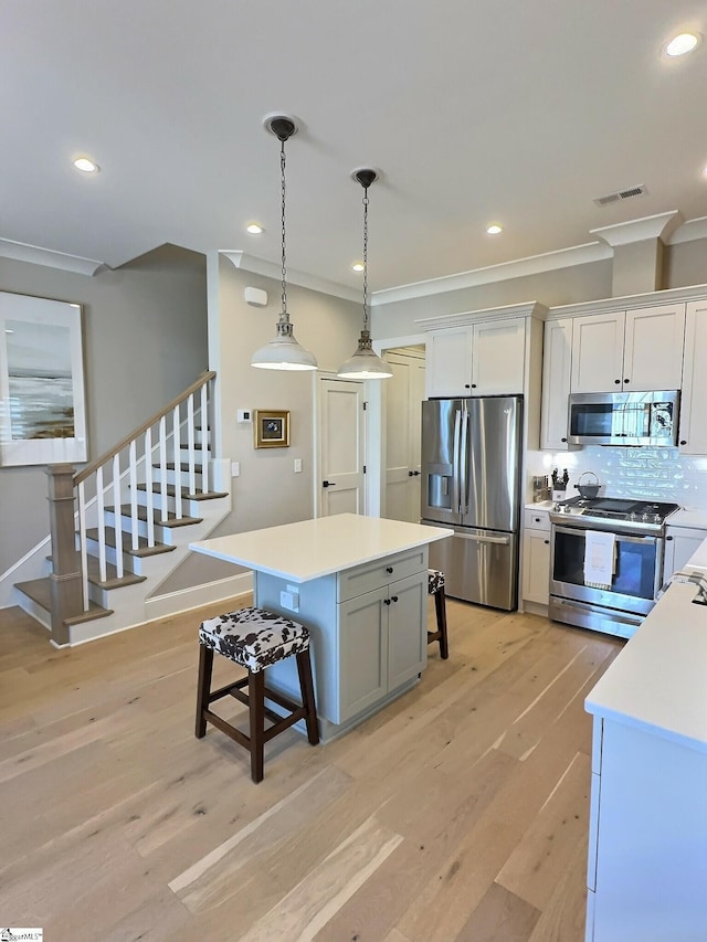 kitchen with a kitchen bar, appliances with stainless steel finishes, tasteful backsplash, a center island, and white cabinetry