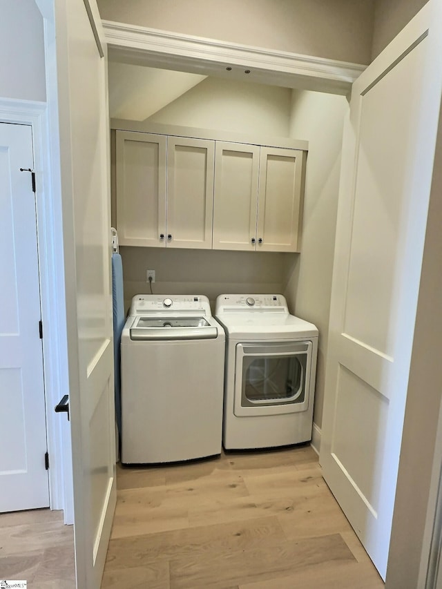 laundry room with washing machine and dryer, cabinets, and light hardwood / wood-style floors