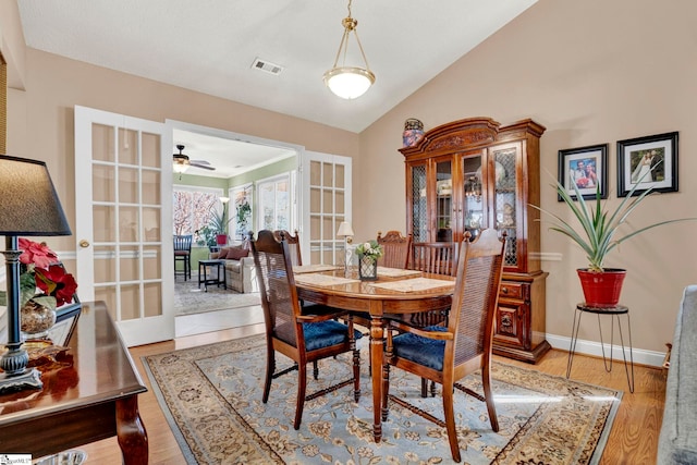 dining room with ceiling fan, french doors, light hardwood / wood-style floors, and vaulted ceiling