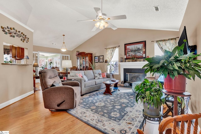 living room featuring a textured ceiling, light wood-type flooring, ceiling fan, and lofted ceiling