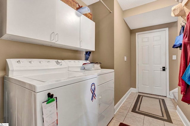 clothes washing area featuring cabinets, light tile patterned floors, a textured ceiling, and washing machine and clothes dryer