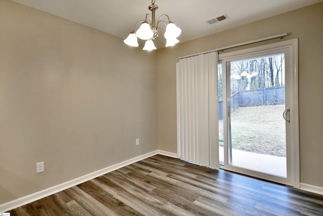 spare room featuring hardwood / wood-style flooring and an inviting chandelier