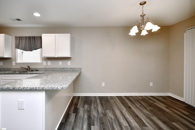 kitchen with an inviting chandelier, sink, hanging light fixtures, light stone countertops, and white cabinetry