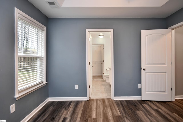 unfurnished bedroom with a spacious closet, a closet, and dark wood-type flooring