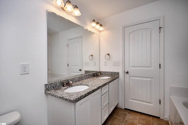 bathroom featuring toilet, vanity, tile patterned floors, and a bathing tub