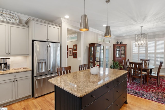 kitchen with high quality fridge, light hardwood / wood-style flooring, a chandelier, a center island, and hanging light fixtures