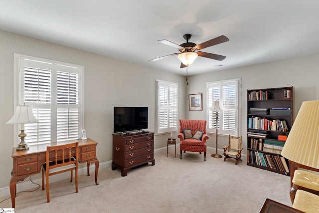 living area with light carpet and ceiling fan