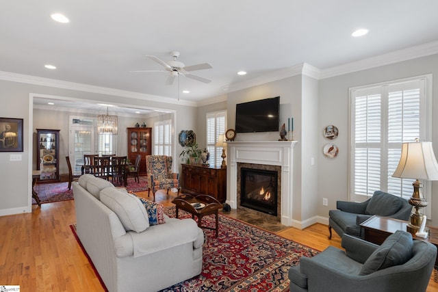 living room featuring ceiling fan, light hardwood / wood-style flooring, a high end fireplace, and crown molding