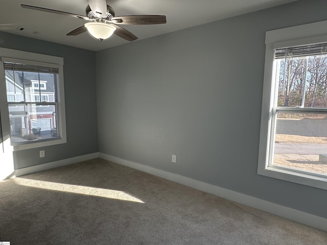 carpeted spare room featuring plenty of natural light and ceiling fan