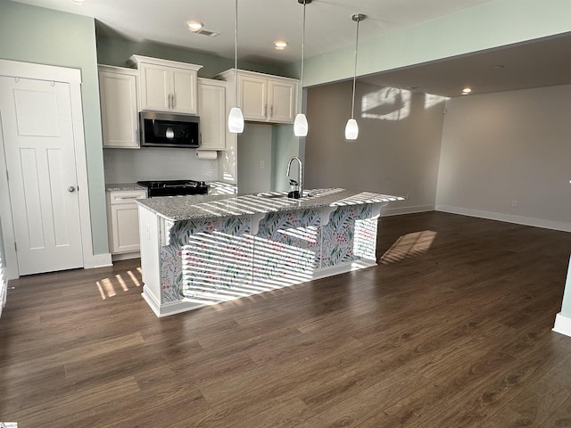 kitchen featuring tasteful backsplash, white cabinetry, black stove, and hanging light fixtures