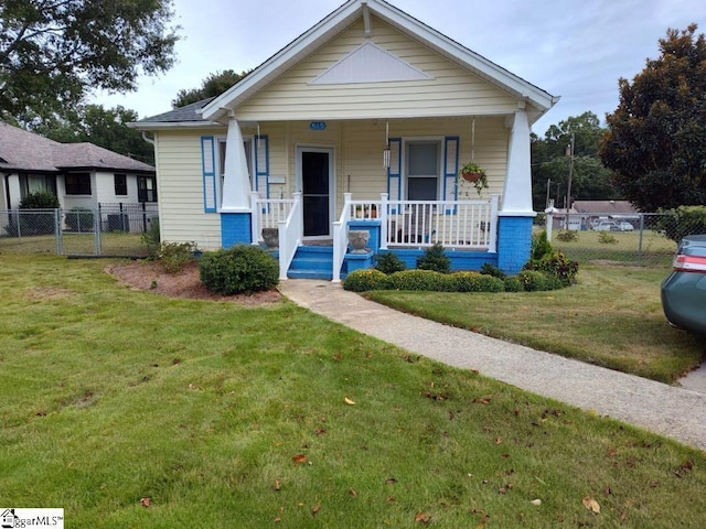 bungalow featuring covered porch and a front yard