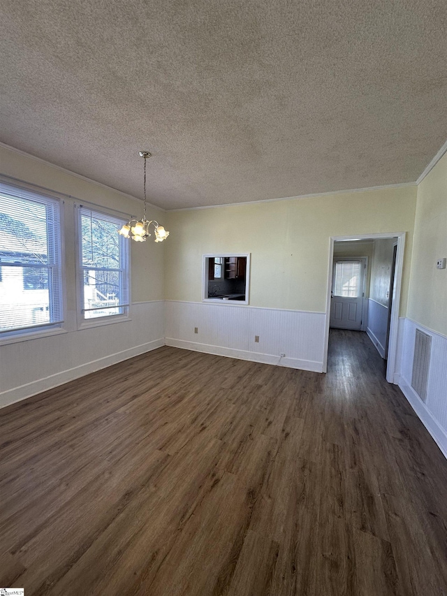 unfurnished dining area featuring dark hardwood / wood-style flooring, a textured ceiling, and an inviting chandelier