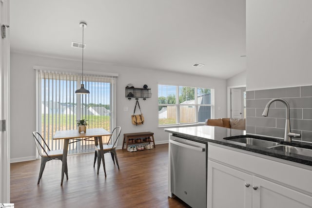 kitchen with dishwasher, dark stone counters, sink, hanging light fixtures, and white cabinetry