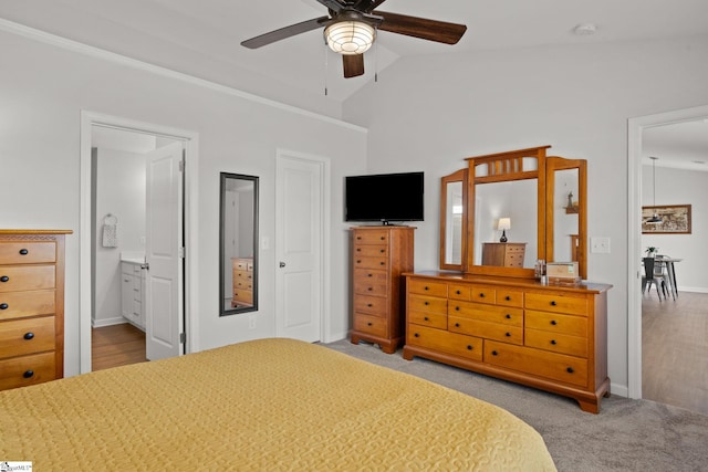 bedroom featuring light carpet, ensuite bathroom, vaulted ceiling, and ceiling fan