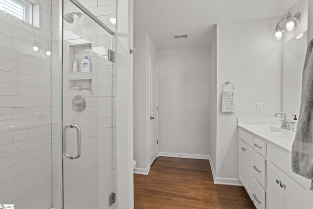 bathroom with toilet, vanity, a shower with shower door, and hardwood / wood-style flooring