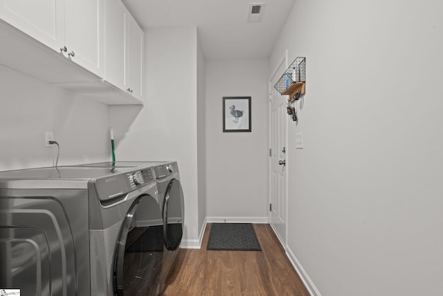 clothes washing area with cabinets, separate washer and dryer, and dark wood-type flooring