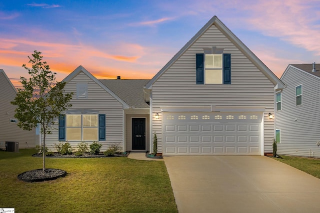 front of property featuring a garage, cooling unit, and a lawn