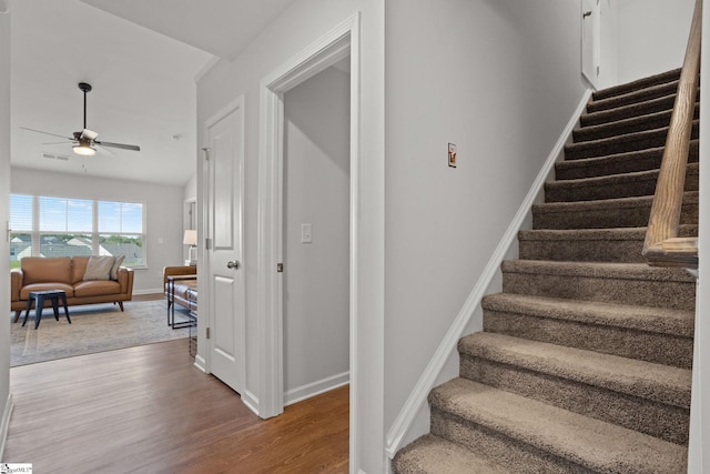 stairs with hardwood / wood-style floors, ceiling fan, and lofted ceiling