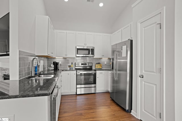 kitchen featuring sink, tasteful backsplash, dark stone countertops, white cabinets, and appliances with stainless steel finishes